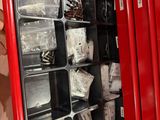 un homme tenant une armoire métallique rouge contenant de nombreux objets