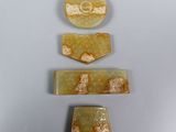 three pieces of yellow jade with gold designs on them on a table