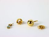 trois paires de boucles d'oreilles en or posées sur une surface blanche, sur fond blanc