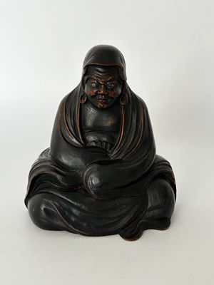 figurine de Bouddha assise sur une surface blanche, avec un fond blanc