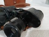 a pair of binoculars sitting on a bed next to a bag
