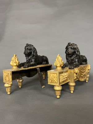 une paire de lions en bronze posés sur un banc sur lequel se trouve un oiseau
