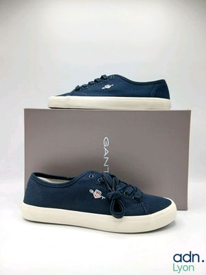 Les chaussures sont bleues et blanches, avec une fleur dessus.