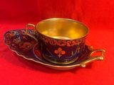 une tasse et une soucoupe posées sur une soucoupe, le tout sur une nappe rouge