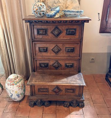une commode en bois dans une pièce, sur laquelle est posé un vase