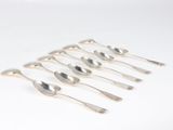 six silver spoons are lined up in a row on a white surface