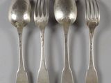 quatre cuillères en argent et une fourchette sont alignées sur une table