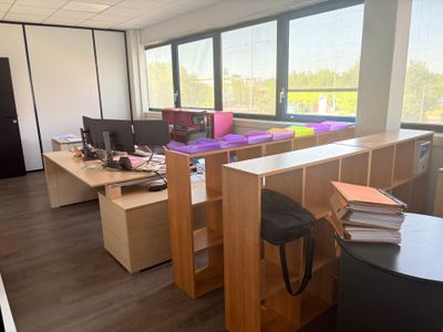 un bureau avec deux ordinateurs et une chaise devant une fenêtre
