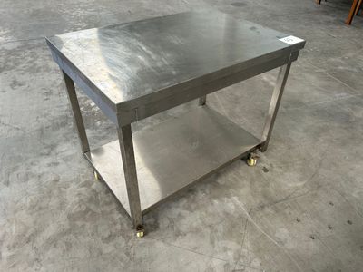 une photo d'une table en acier inoxydable montée sur roulettes dans un entrepôt