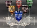 six verres à pied de couleurs différentes sont posés sur un socle transparent