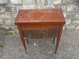 a small table with a drawer on it in front of a stone wall