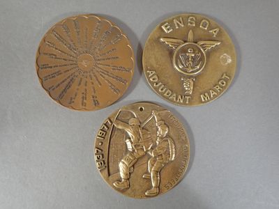 three gold medals are shown on a table with a white background
