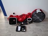 une veste rouge et un sac rouge posés par terre à côté d'un ventilateur