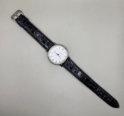 une image représentant une montre en noir et blanc posée sur une surface blanche