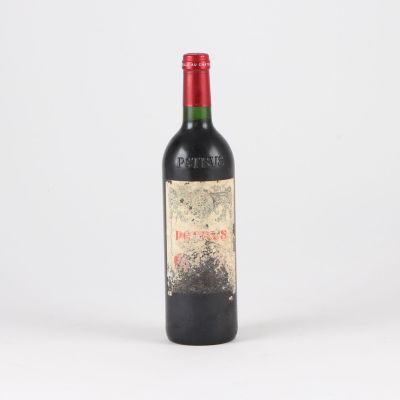an old bottle of red wine sitting on top of a white table
