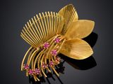 an image of a gold brooch with pink stones on a black background