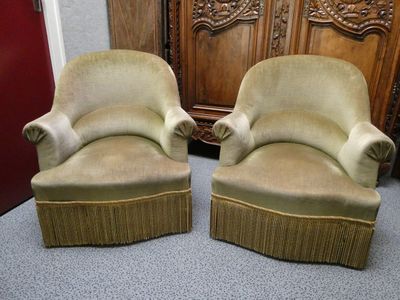 une paire de fauteuils rembourrés beiges placés devant un meuble en bois