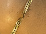 quelqu'un porte au poignet un bracelet en or muni d'une chaîne