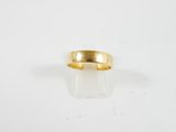 gros plan d'une bague en or sur une surface blanche