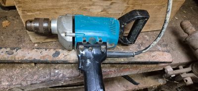 une perceuse bleue posée sur un morceau de bois
