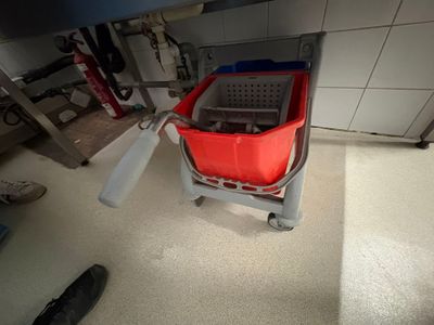 a red bucket sitting on top of a gray cart