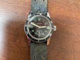 the watch is sitting on a wooden table with a black strap