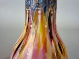 a colorful glass vase sitting on a table with a silver lid