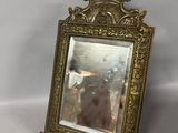 an antique brass framed mirror with a bird on top of it
