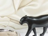 une figurine de chat noir posée à côté d'un plateau en argent