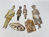 several antique silver and gold metal charms on a white surface