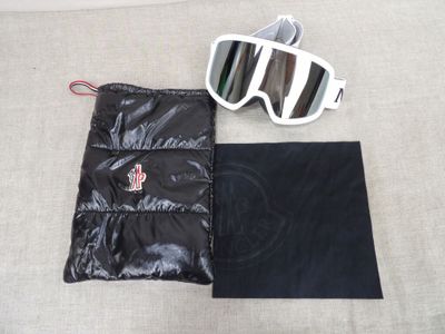 une paire de lunettes de soleil et une pochette posées sur un lit