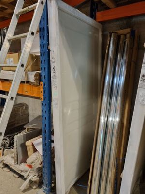 un réfrigérateur blanc posé dans un entrepôt, à côté d'une échelle