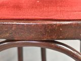 a close up of a wooden stool with a red cushion
