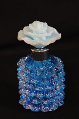 une bouteille en verre bleue contenant une fleur blanche