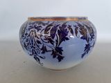 a blue and white vase with a gold rim on a table