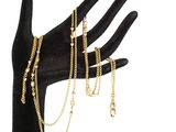 La main tient un bracelet en chaîne d'or et un gant noir.