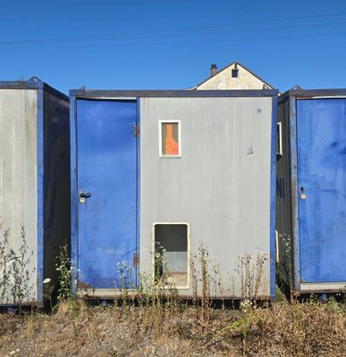 three portable toilets sitting in a field next to each other