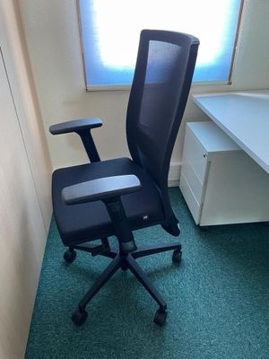 a black office chair sitting in front of a desk