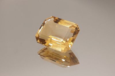 a close up of a yellow topazte stone on a white surface
