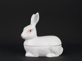 un lapin en porcelaine blanche posé sur une surface noire