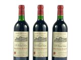 trois bouteilles de vin rouge posées l'une à côté de l'autre sur une surface blanche