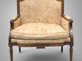 une vieille chaise avec un dossier recouvert d'un tissu à motifs floraux et un cadre en bois
