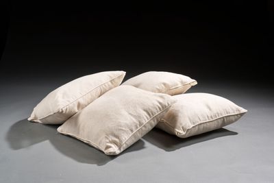 trois oreillers blancs posés les uns à côté des autres sur un sol gris