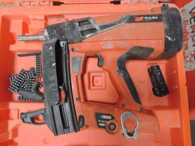 une boîte à outils orange contenant un marteau, un tournevis, un autre tournevis et d'autres outils