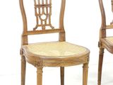 two wooden chairs with wicker seats and a cane back