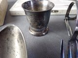 a silver cup sitting on top of a table next to other silver utensils