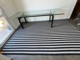 un tapis à rayures noires et blanches avec une table en verre