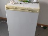 a small white refrigerator in the corner of a room