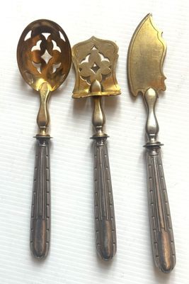 trois cuillères et une spatule sont posées sur une surface blanche