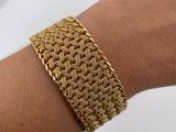 a close up of a person ' s arm wearing a gold bracelet